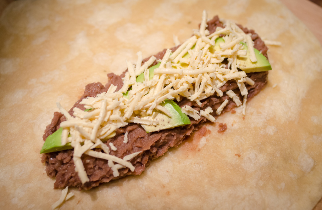 vegan burrito fillings, cheese and avocado on tortilla