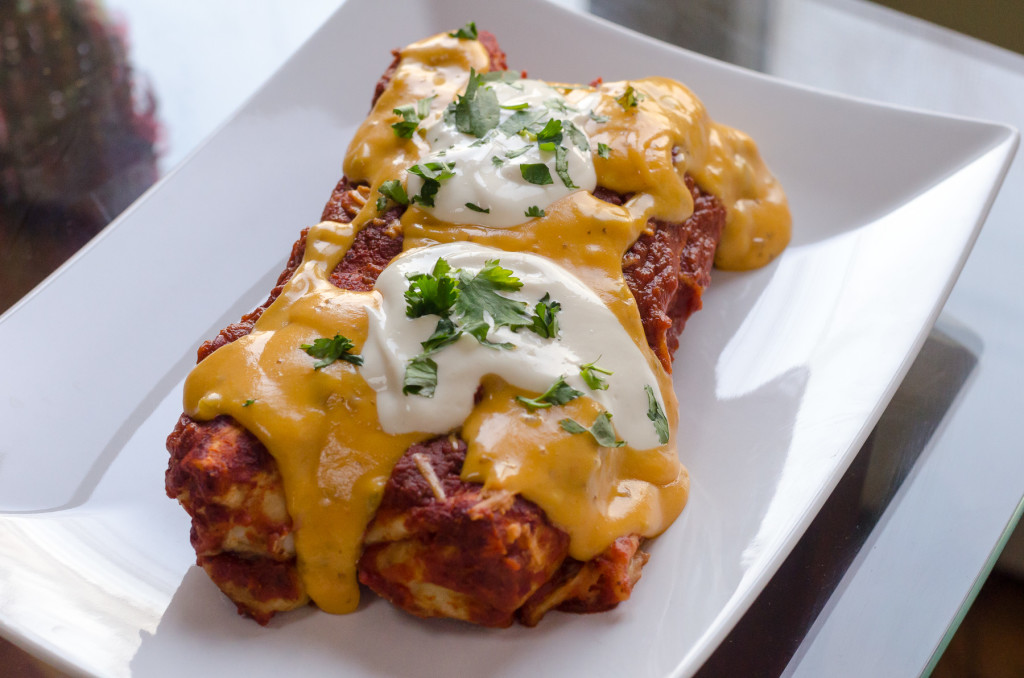 Delicious black bean and veggie enchiladas, topped with the amazing nacho cheese sauce and sour cream. Dig in!