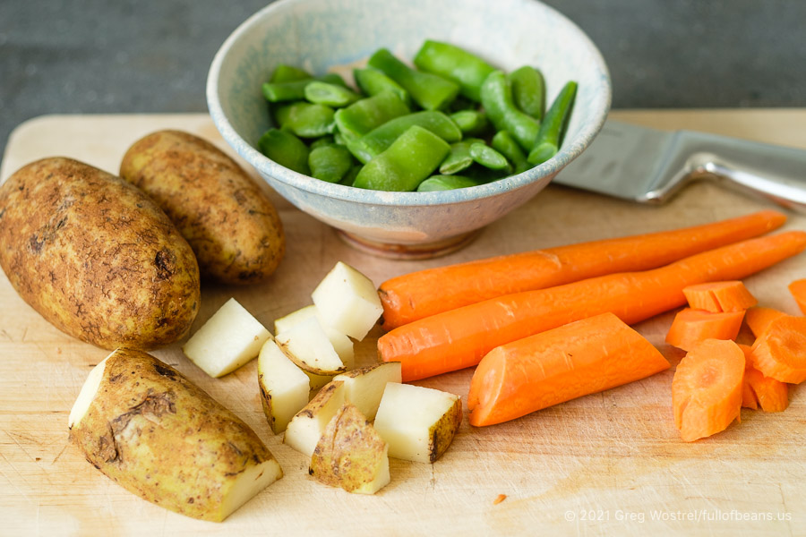 potatoes, beans, and carrots on a cutting board