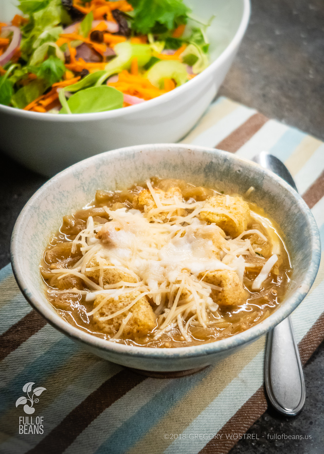 vegan onion soup in a bowl, topped with cheese and croutons - Full of Beans
