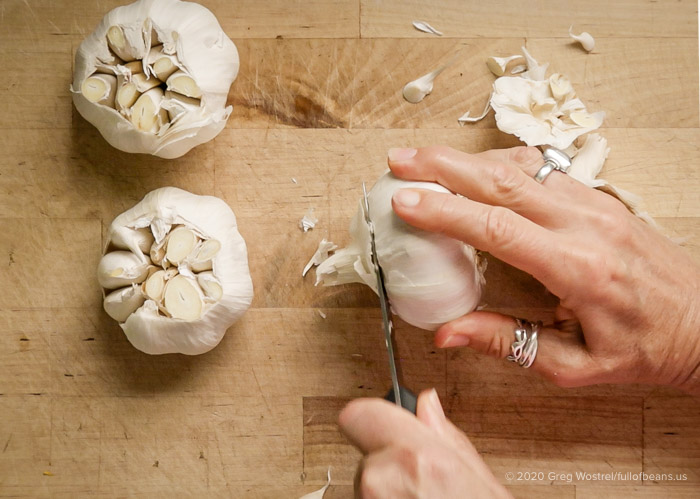 preparing roasted garlic by slicing the tops of heads of garlic