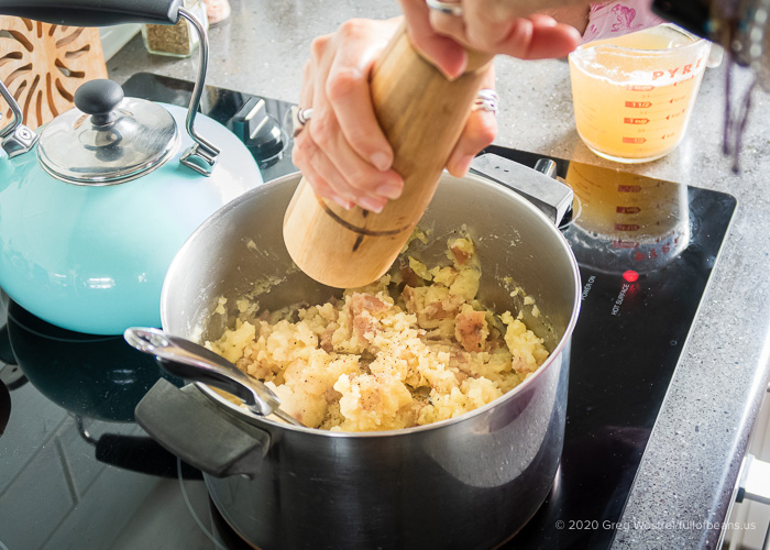 grinding black paper into the garlic mashed potatoes 