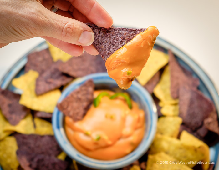 Our Nacho Cheese Sauce on a blue corn chip