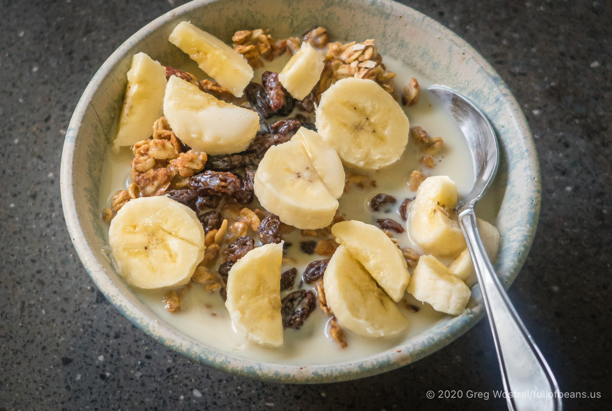 easy almond maple granola in a bowl with bananas and raisins