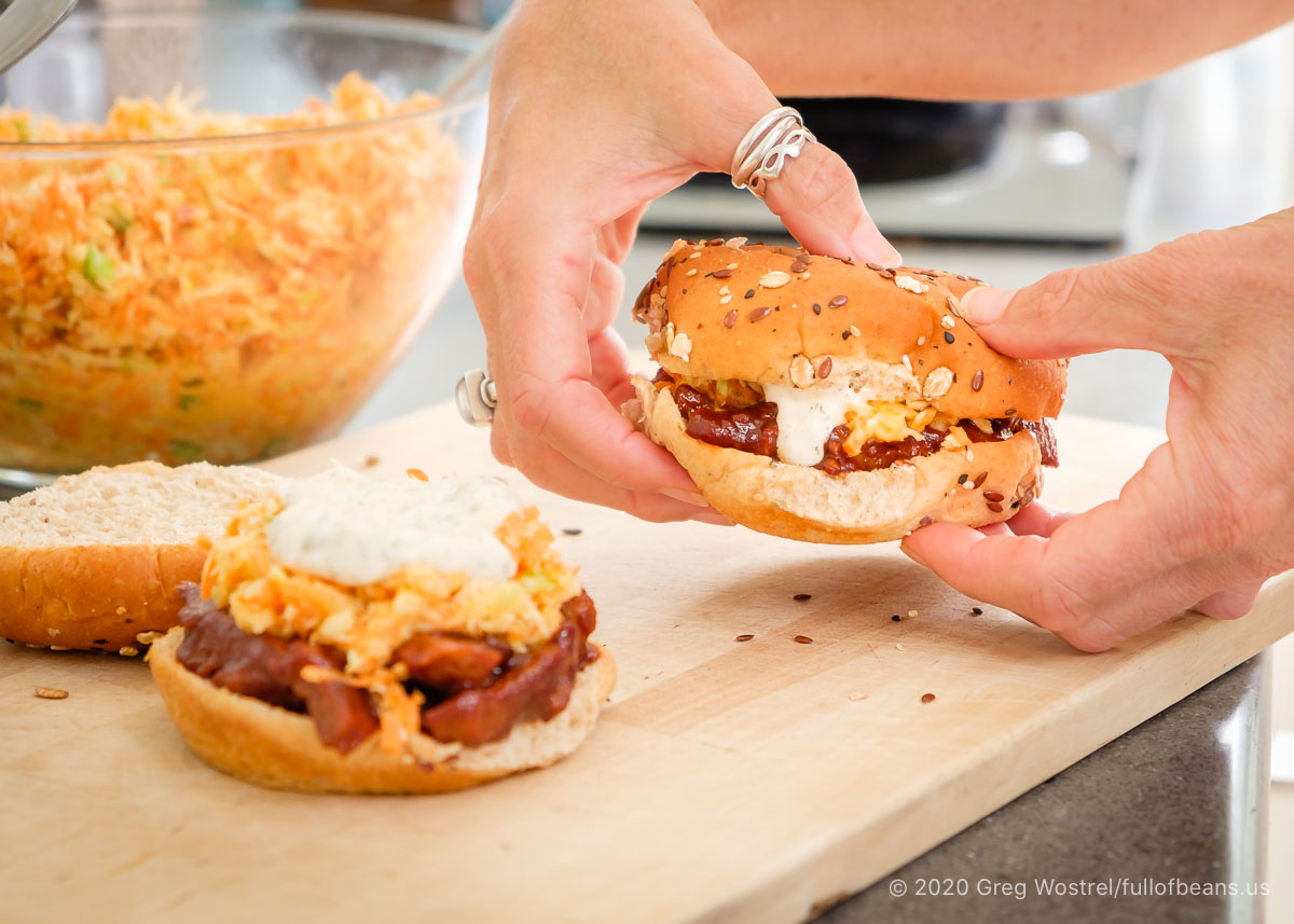 BBQ Seitan sandwich ready to eat and being picked up by a pair of hands