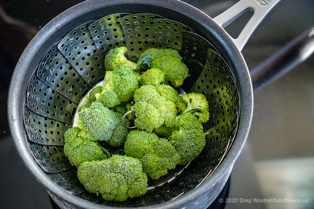 raw broccoli in a stainless steel veggie steamer basket