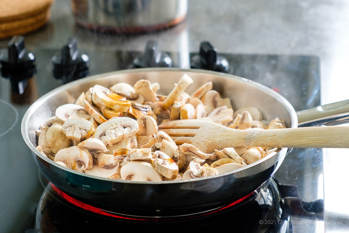 sliced mushrooms cooking in a pan on a stove