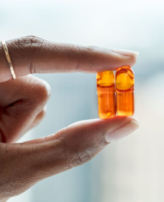 two Juice Plus Omega Capsules between a persons fingers