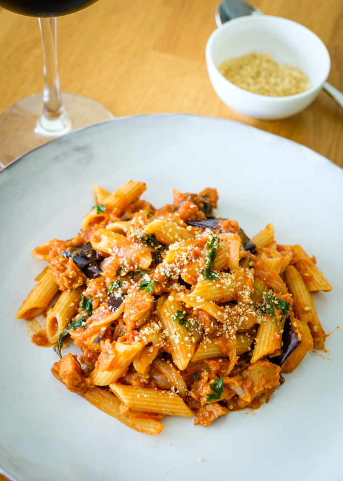 vegan penne with sausage and eggplant served on a white plate