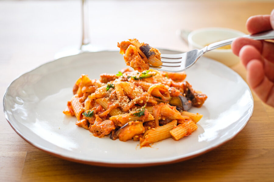 vegan penne with sausage and eggplant served on a white plate