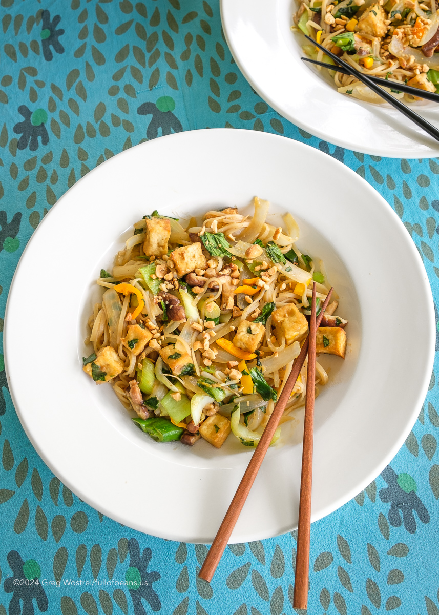 A plate of vegan pad thai on a blue table cloth